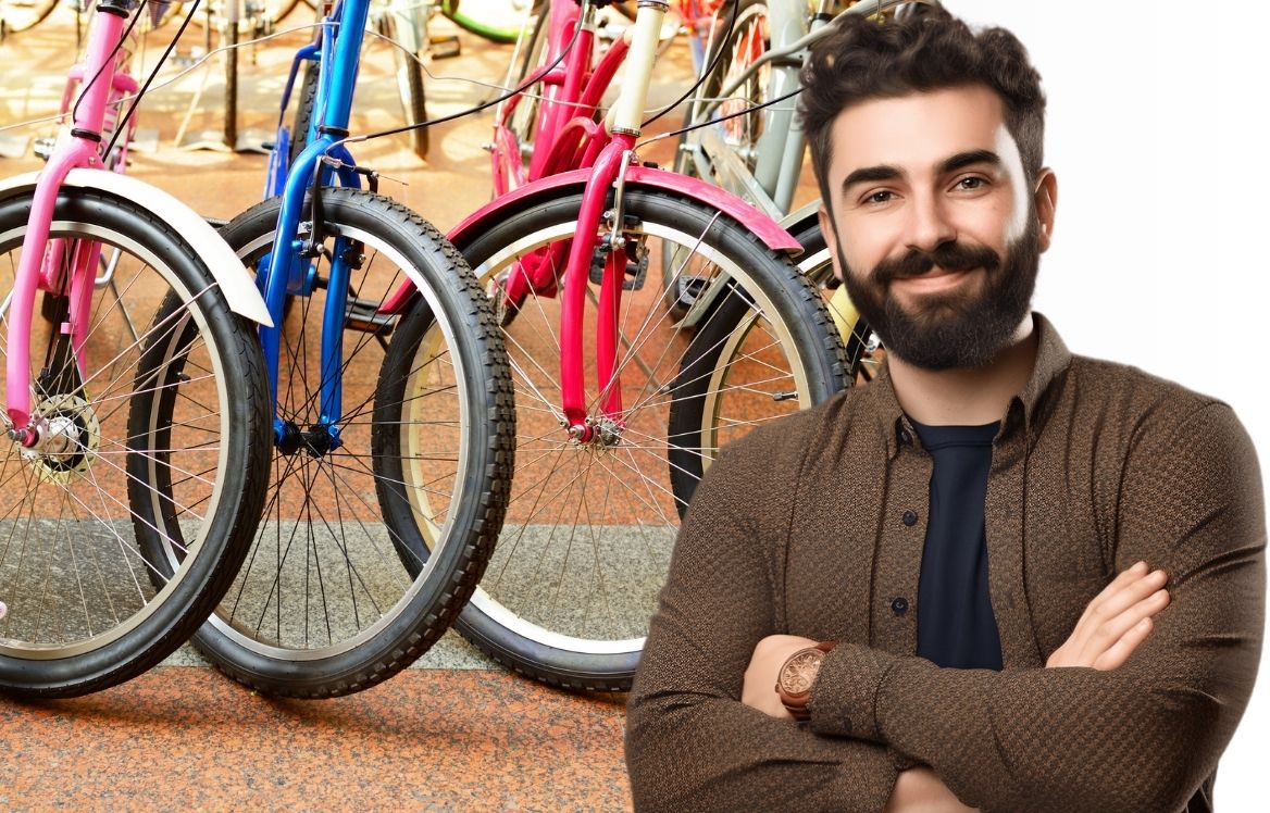 homme bras croisé qui vous regarde et dernière lui, on voit des roues de vélo de différentes couleurs