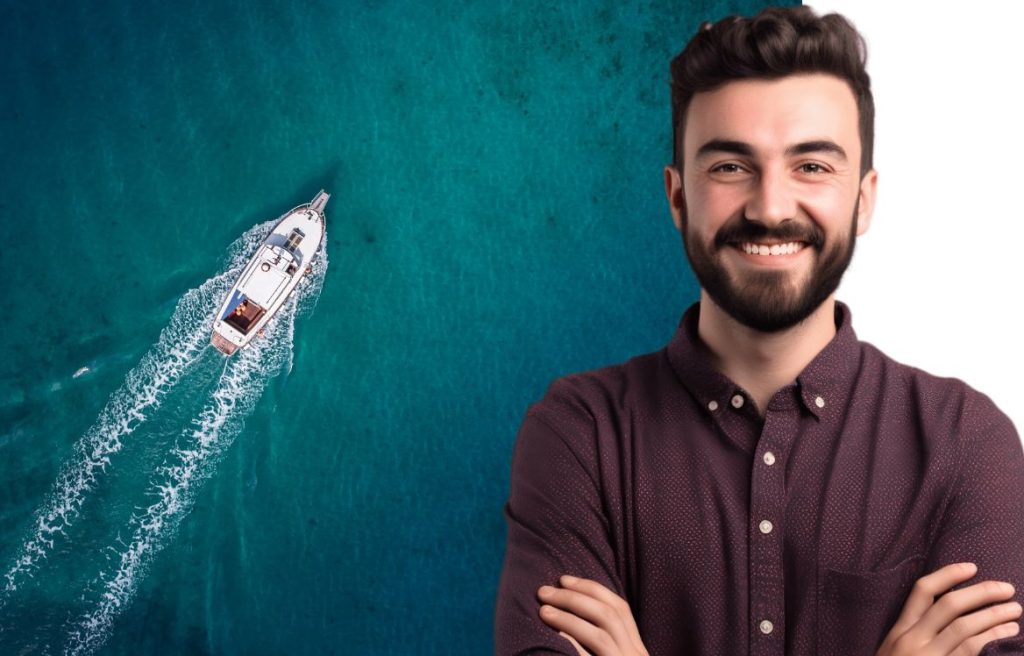 Homme souriant les bras croisés et derrière lui il y à la mer vu de haut avec un yacht qui navigue